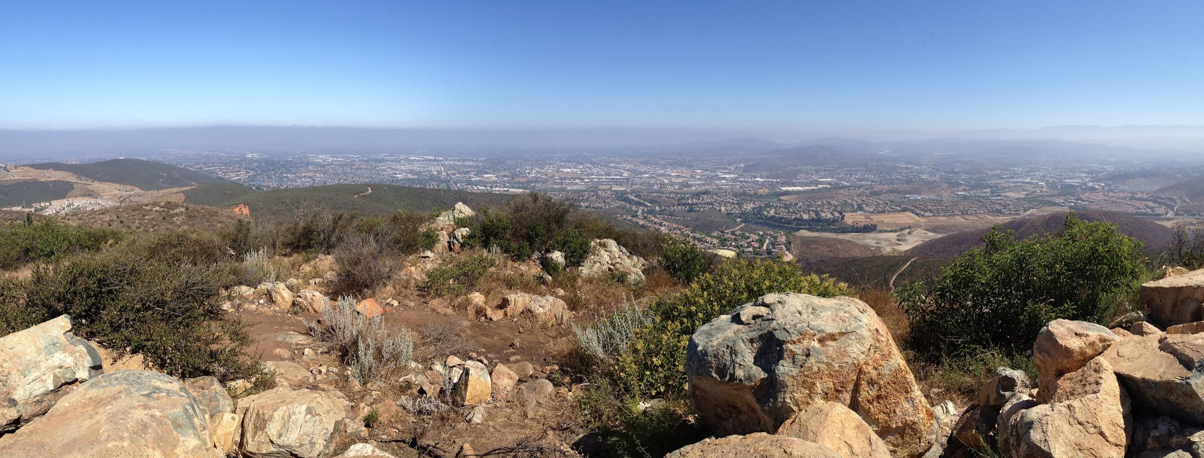 Panorama from the rocky summit of Double Peak Park looking north over the San Marcos valley and hills in light haze.