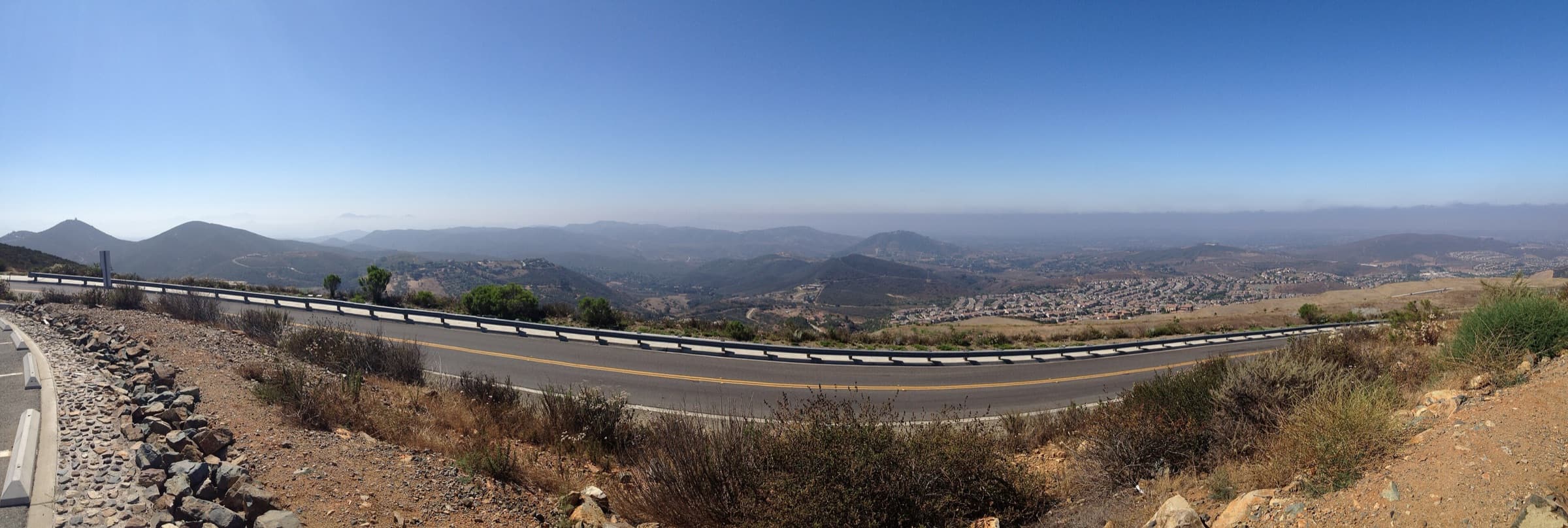 Panorama looking south from Double Peak Park, with the summit road curving past hills and valley neighborhoods.