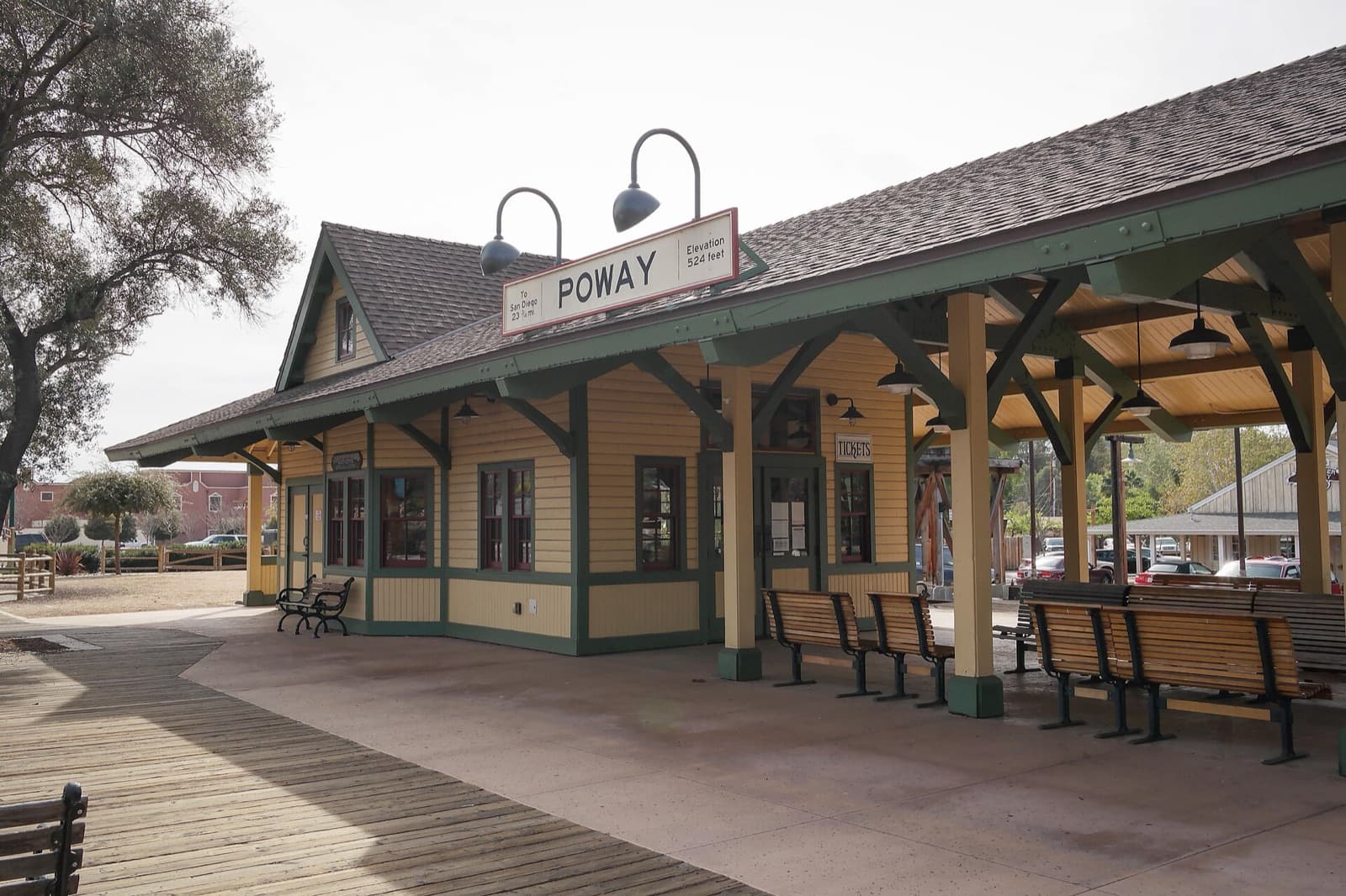 The yellow and green Poway train depot at Old Poway Park, with its station sign and benches under the platform roof.